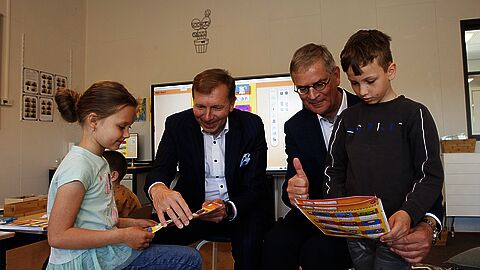 Burgemeester Gert-Jan Kats en wethouder Marco0 Verloop kijken mee met Oekraïense kinderen in taalschool Pimpelmees. 